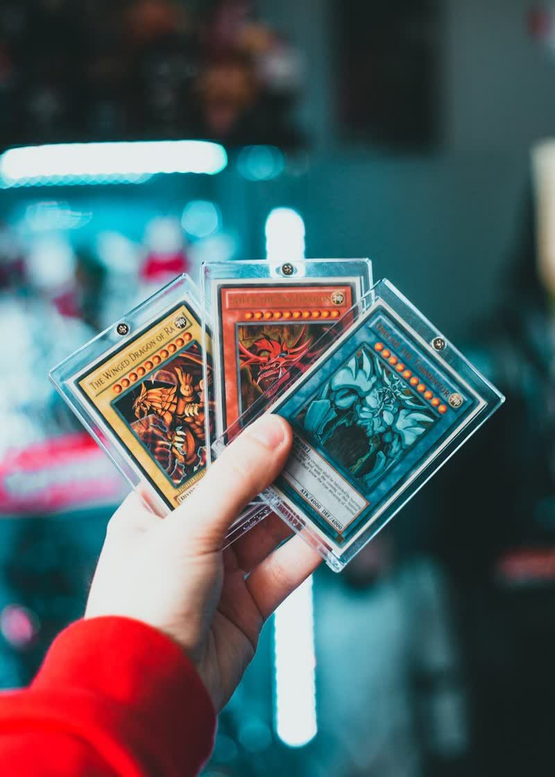 Tres cartas de colección en fundas rígidas sostenidas en la mano
